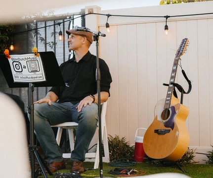 Jon Flietstra performing on acoustic guitar under string lights